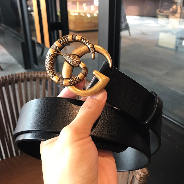 Black leather belt with gold-tone buckle detail held in hand