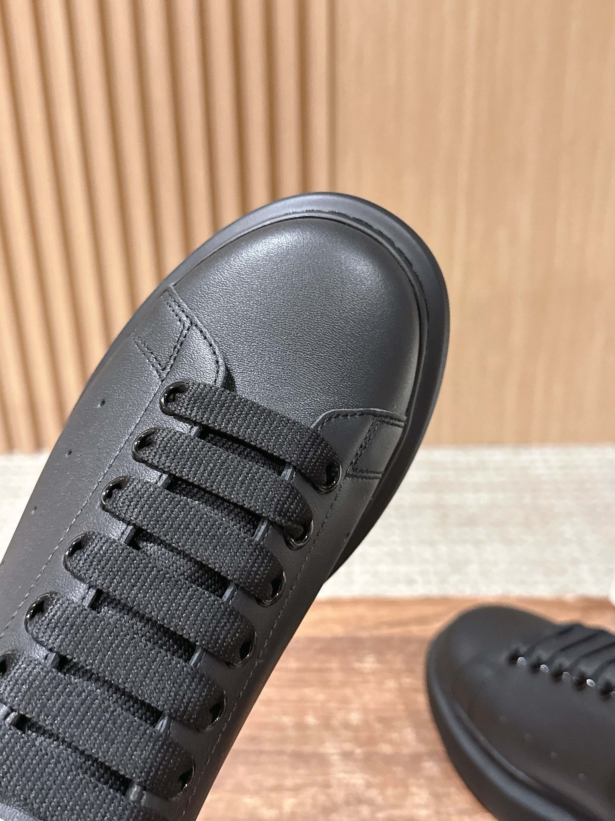 Close-up of black sneaker upper with black lace and stitched side panel