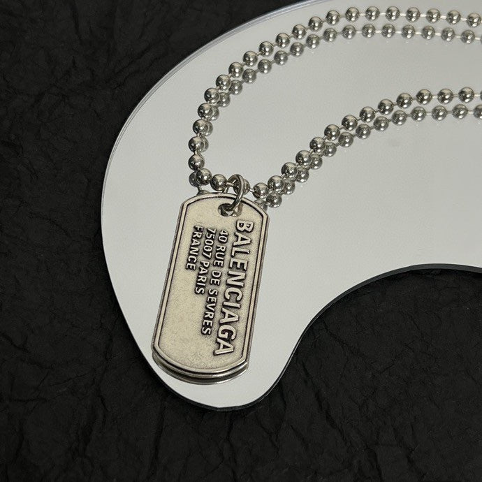 Close-up of engraved dog tag pendant on silver-tone bead chain