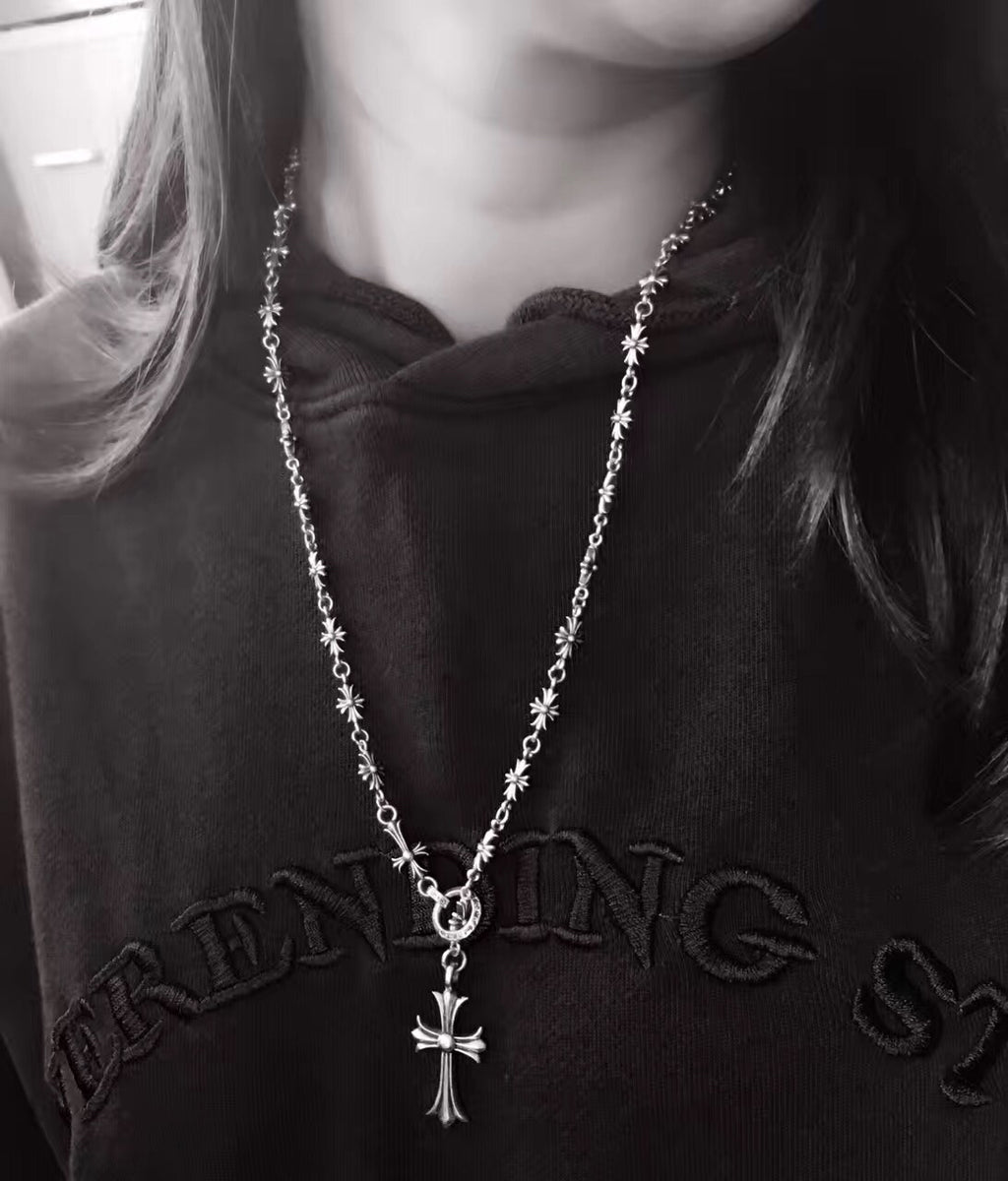 Silver-tone cross charm chain necklace with small star links, on dark hoodie