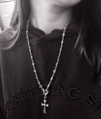 Silver-tone cross charm chain necklace with small star links, on dark hoodie
