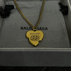 Gold heart pendant necklace with logo heart charm on a fabric jewelry tray.