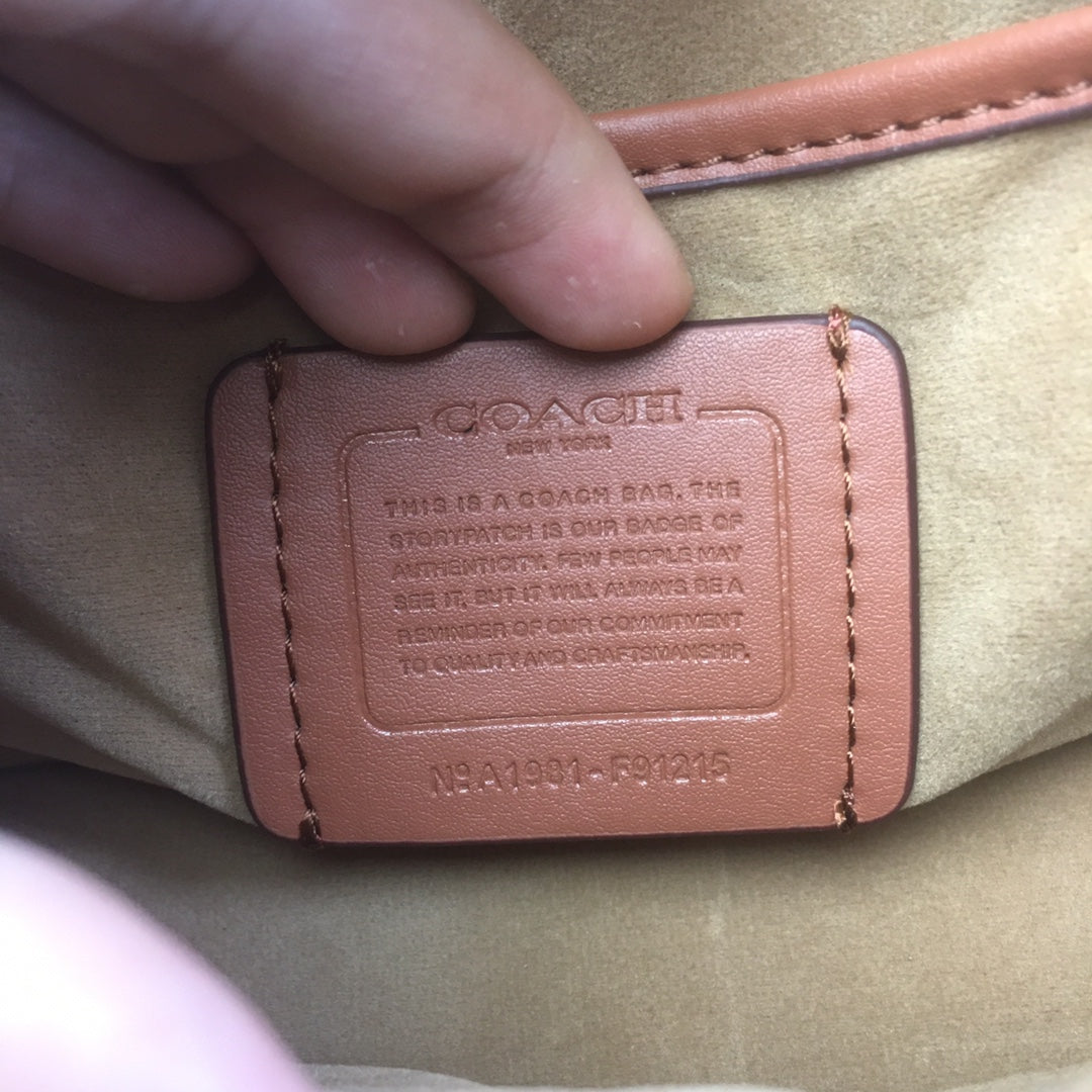 Coah bag interior label close-up with stamped text and stitched edge