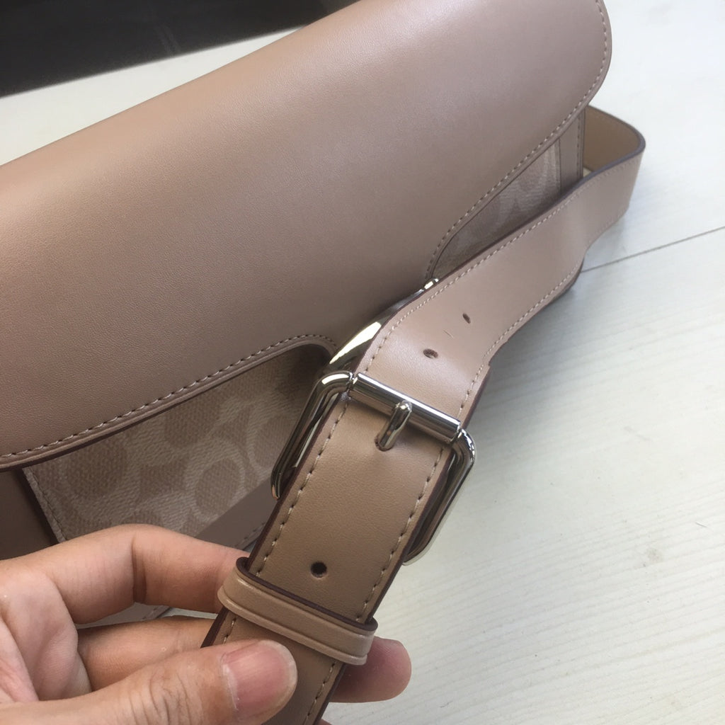 Coah bag strap close-up with adjustable buckle and stitched trim