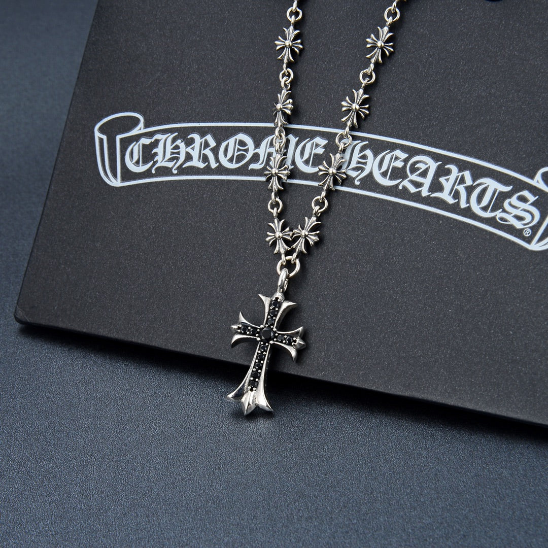 Silver-tone cross pendant necklace with flower charms and dark purple gem center