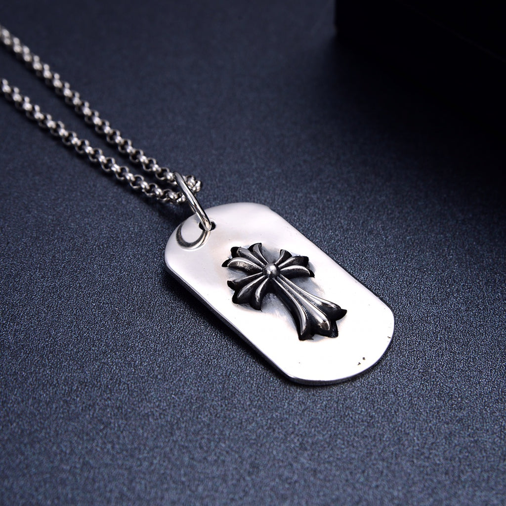 Dog tag pendant necklace close-up with silver flower on white oval tag
