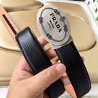 Prada belt pair view: black ribbed straps with tan underlay and oval logo label