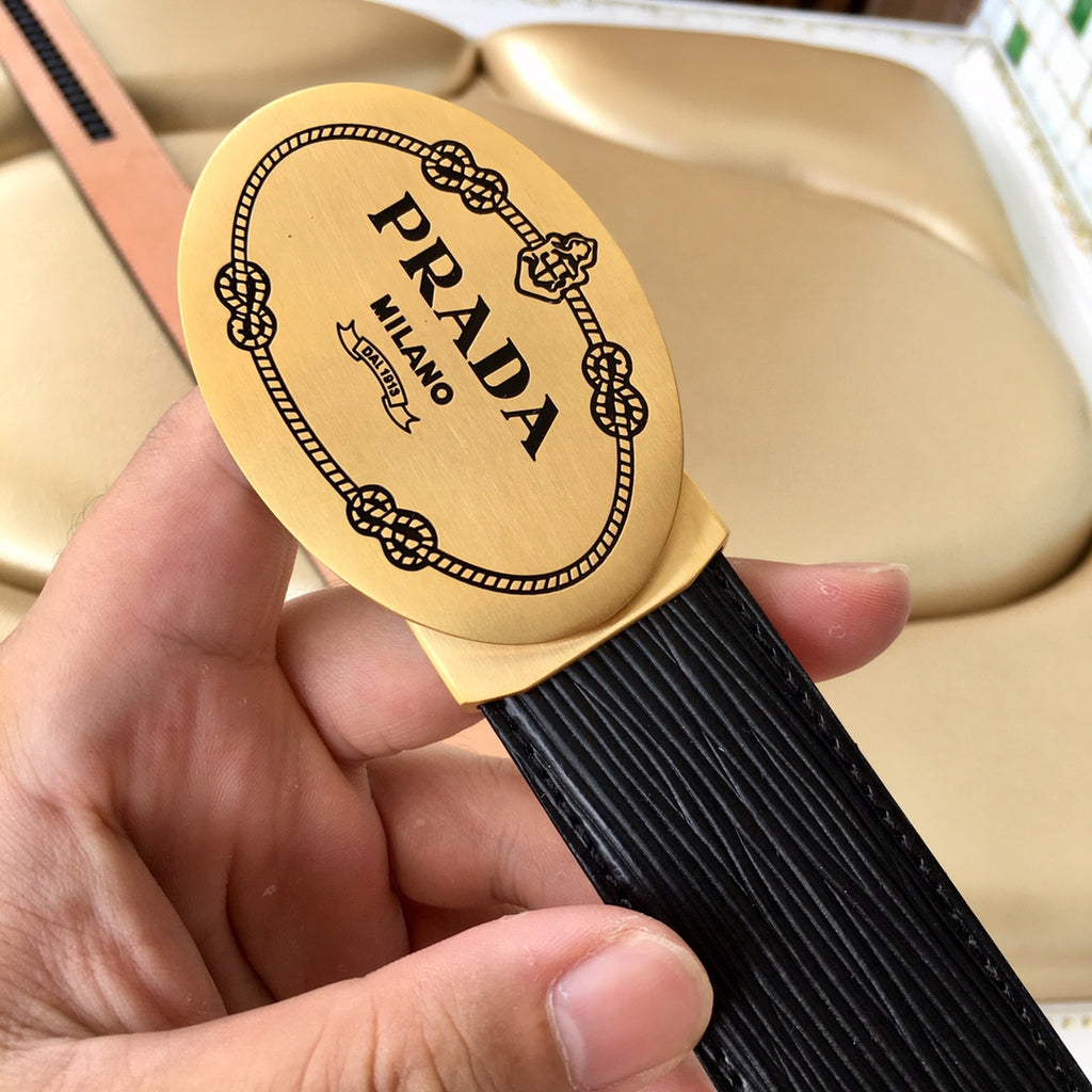 Prada belt logo plate close-up on black textured strap with tan strap edge.