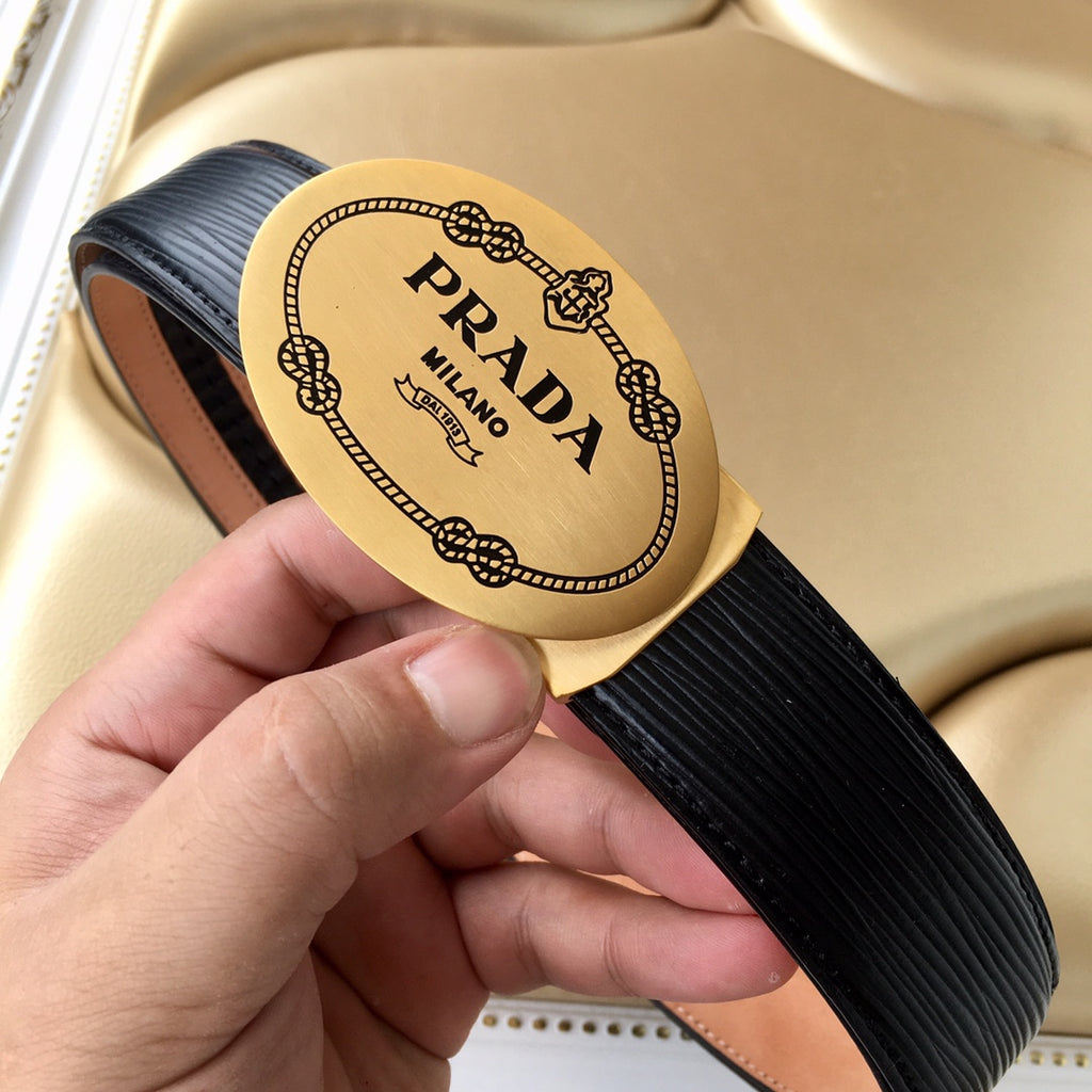 Prada belt buckle close-up on black ribbed strap with tan trim, held in hand.