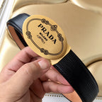 Prada belt buckle close-up on black ribbed strap with tan trim, held in hand.