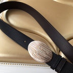 Prada belt with dark textured leather strap and oval silver logo buckle on bag