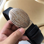 Prada belt oval silver logo buckle on dark textured leather strap, side view