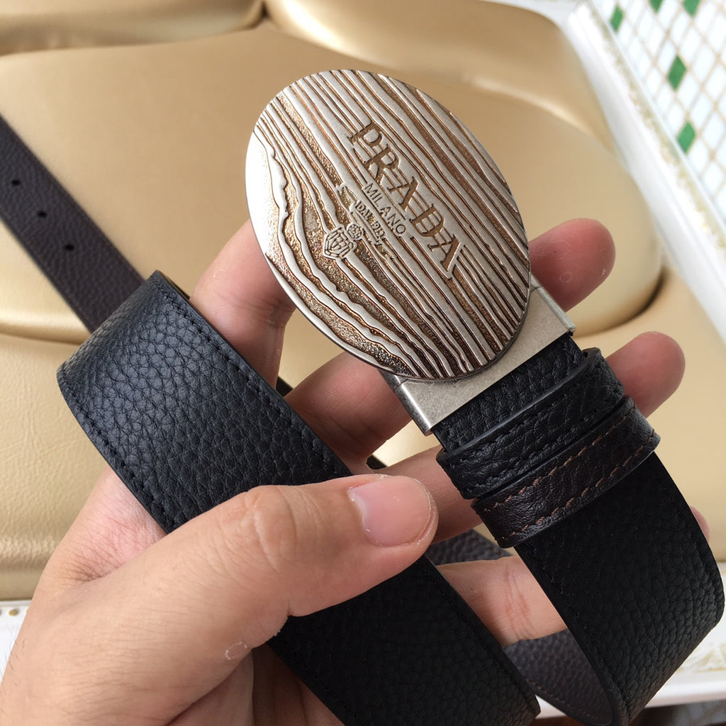 Prada belt with dark textured leather strap and oval silver logo buckle in hand