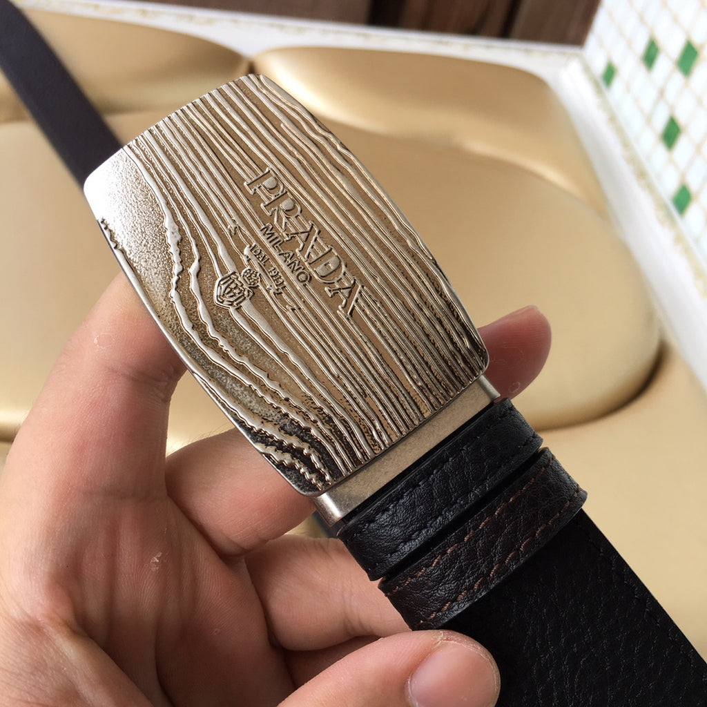 Prada belt buckle close-up with silver engraved logo on dark grained leather