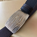 Prada belt buckle detail: silver engraved plate on dark grained leather strap