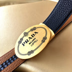 Prada belt with gold oval logo buckle on dark blue and tan strap panel.