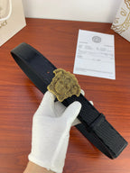 Black embossed belt with gold Medusa-style buckle and pin closure.