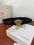 Black embossed belt with gold Medusa-style buckle and visible pin-hole strap.