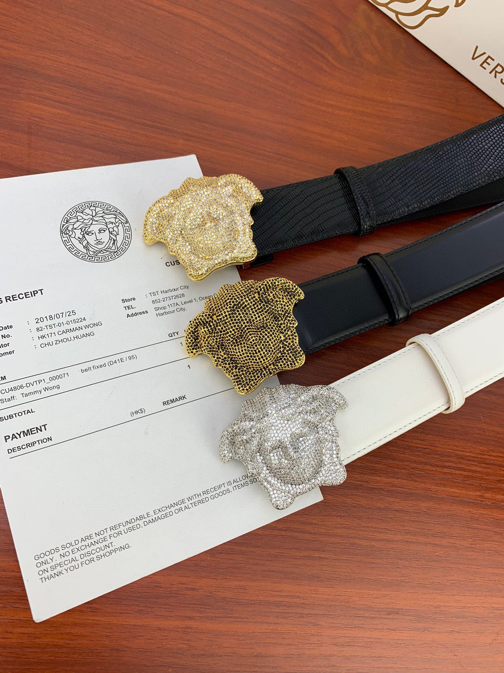Two belts with textured straps and gold-toned emblem buckles