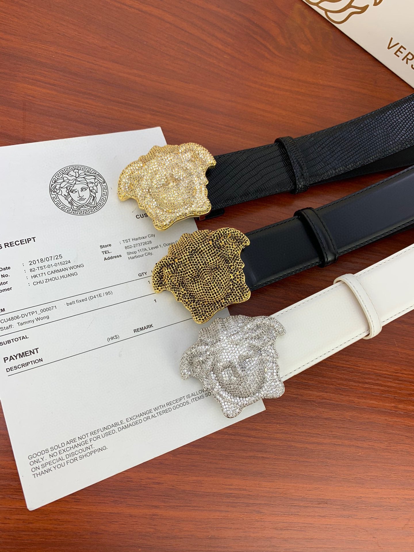 Two belts with textured straps and gold-toned emblem buckles