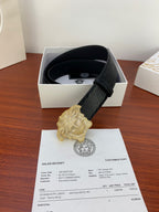Black textured belt with gold emblem buckle in an open gift box