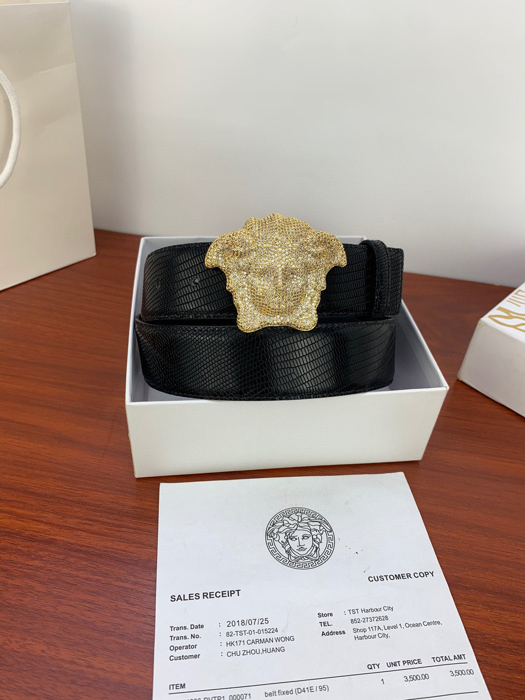 Black belt with gold emblem buckle in a white shoe-box-style holder