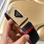 Prada belt buckle view: silver logo plaque on black strap with burgundy leather strip.