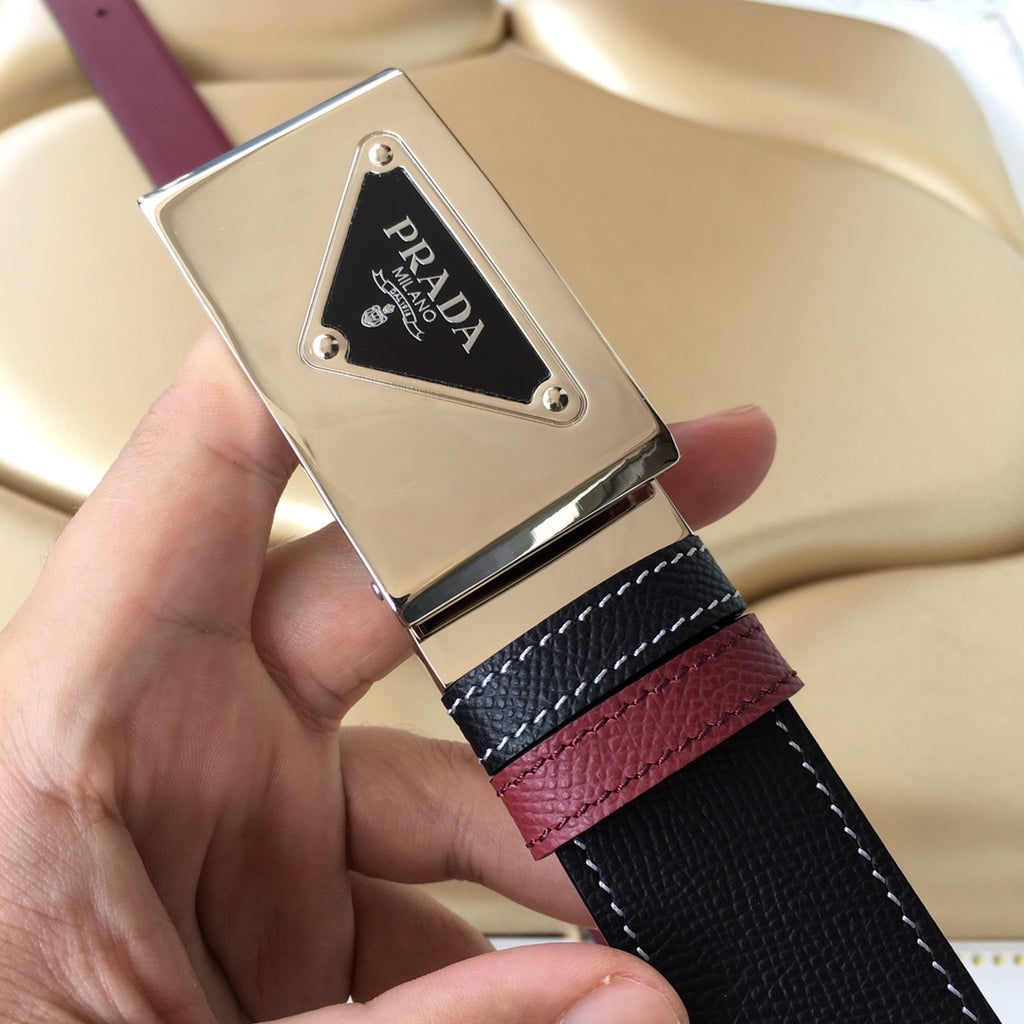 Prada belt logo close-up: silver buckle with PRADA emblem on black textured strap.