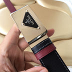 Prada belt logo close-up: silver buckle with PRADA emblem on black textured strap.