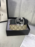 Gucci belt in box: black leather strap with interlocking G buckle and tan GG monogram panel.