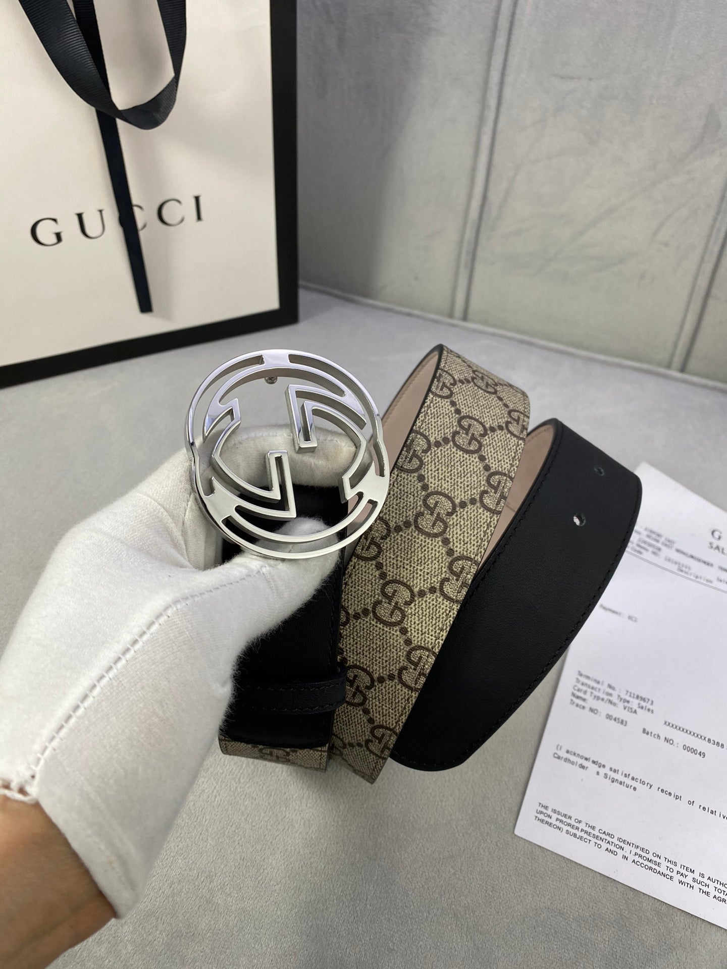 Gucci belt with silver-tone interlocking G buckle and GG monogram canvas section on black strap.