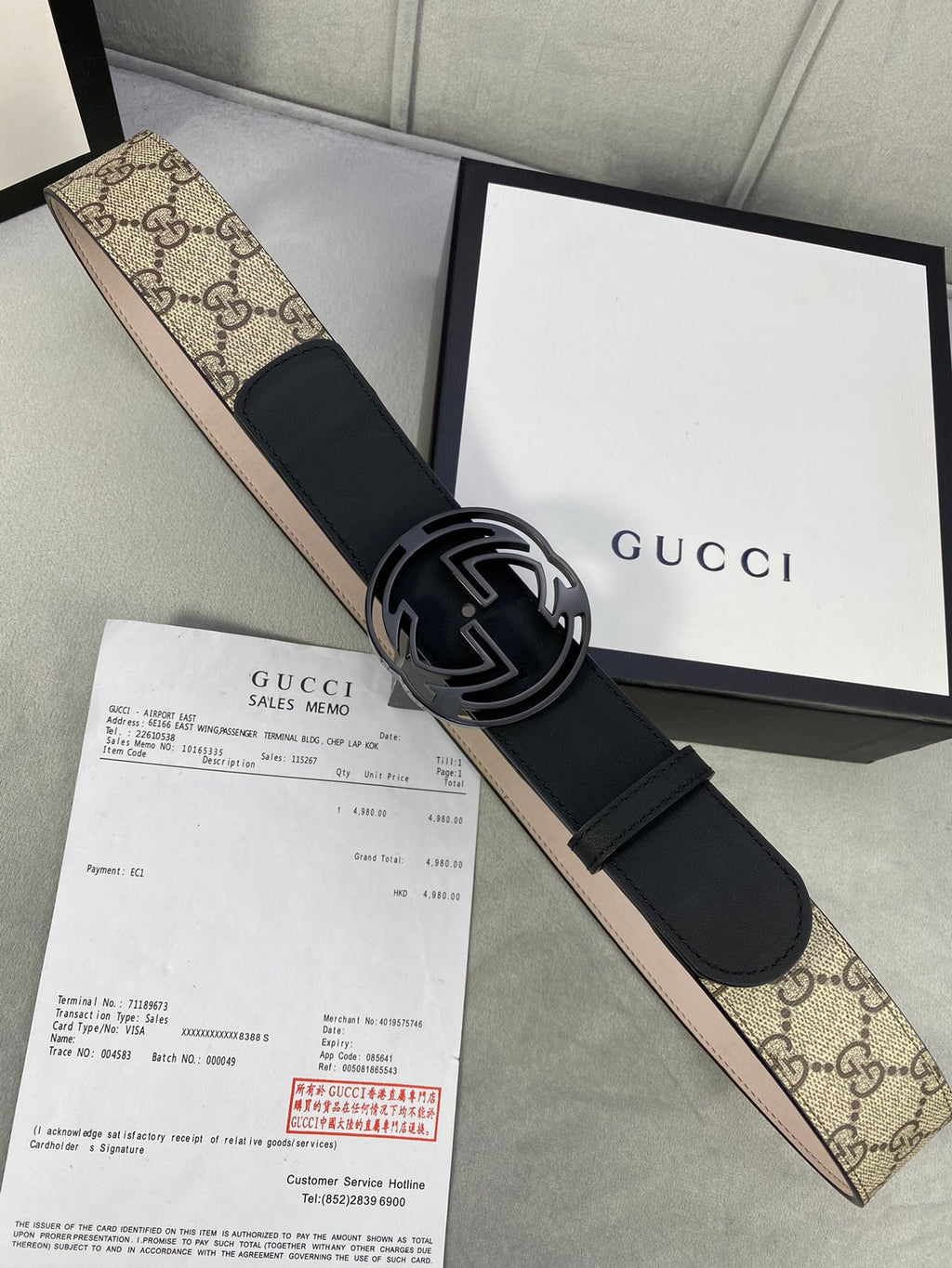 Gucci belt with black leather strap, interlocking G buckle, and GG monogram canvas panel.
