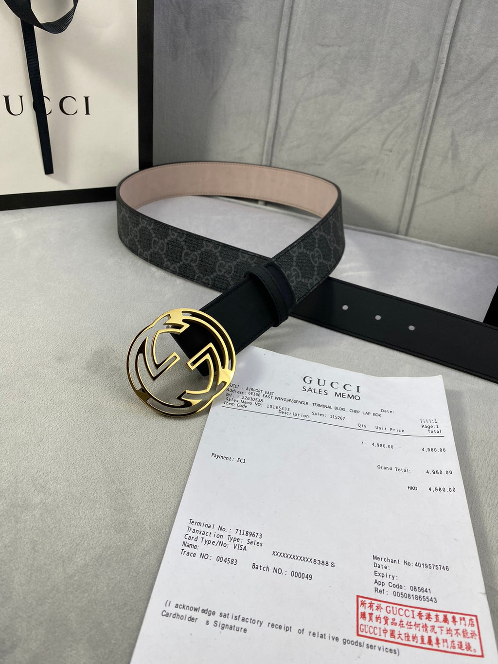 Black GG monogram belt with gold-toned round interlocking buckle and tan underside.