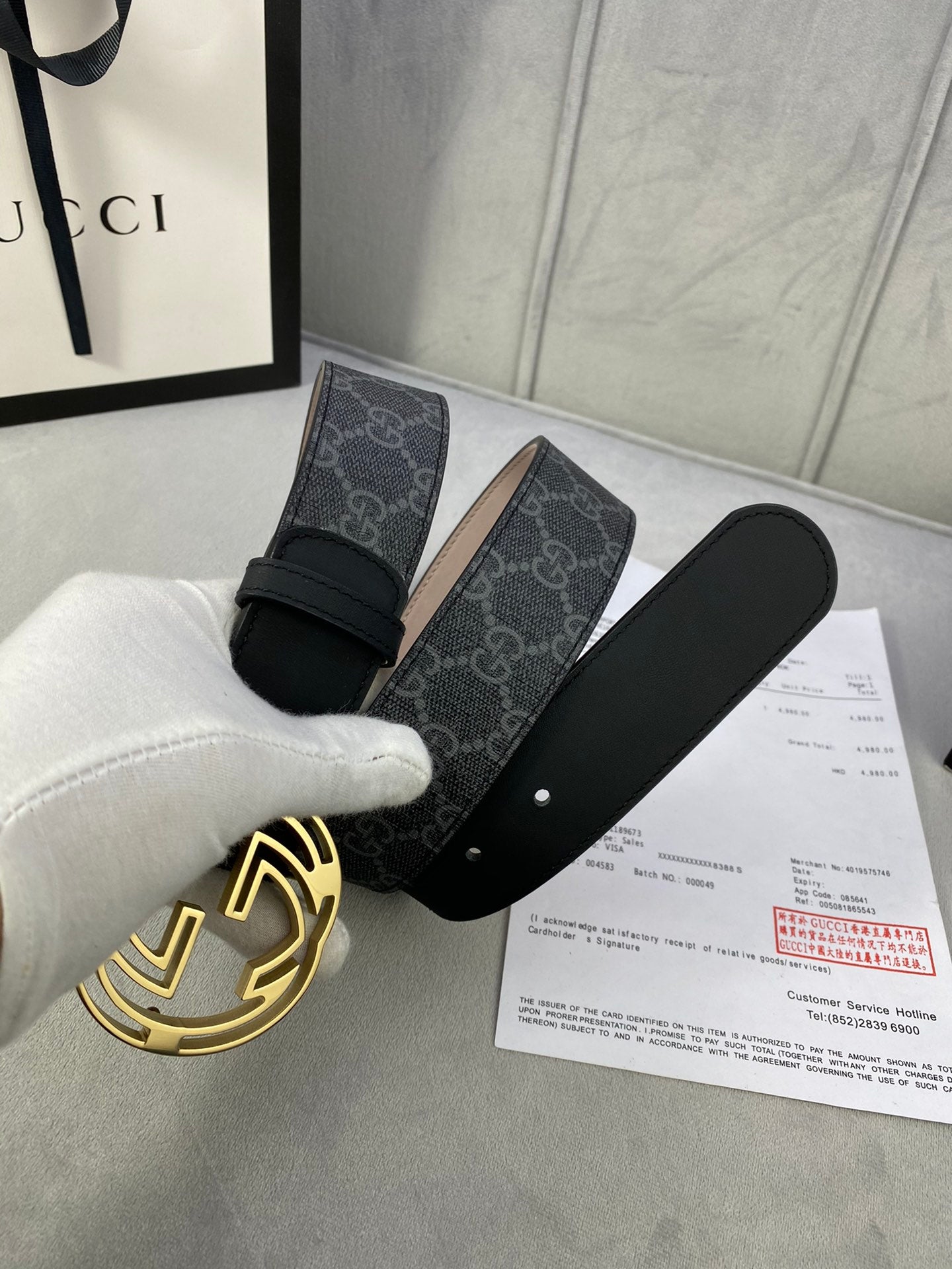 Black GG monogram belt with gold-toned interlocking logo buckle and leather strap ends.