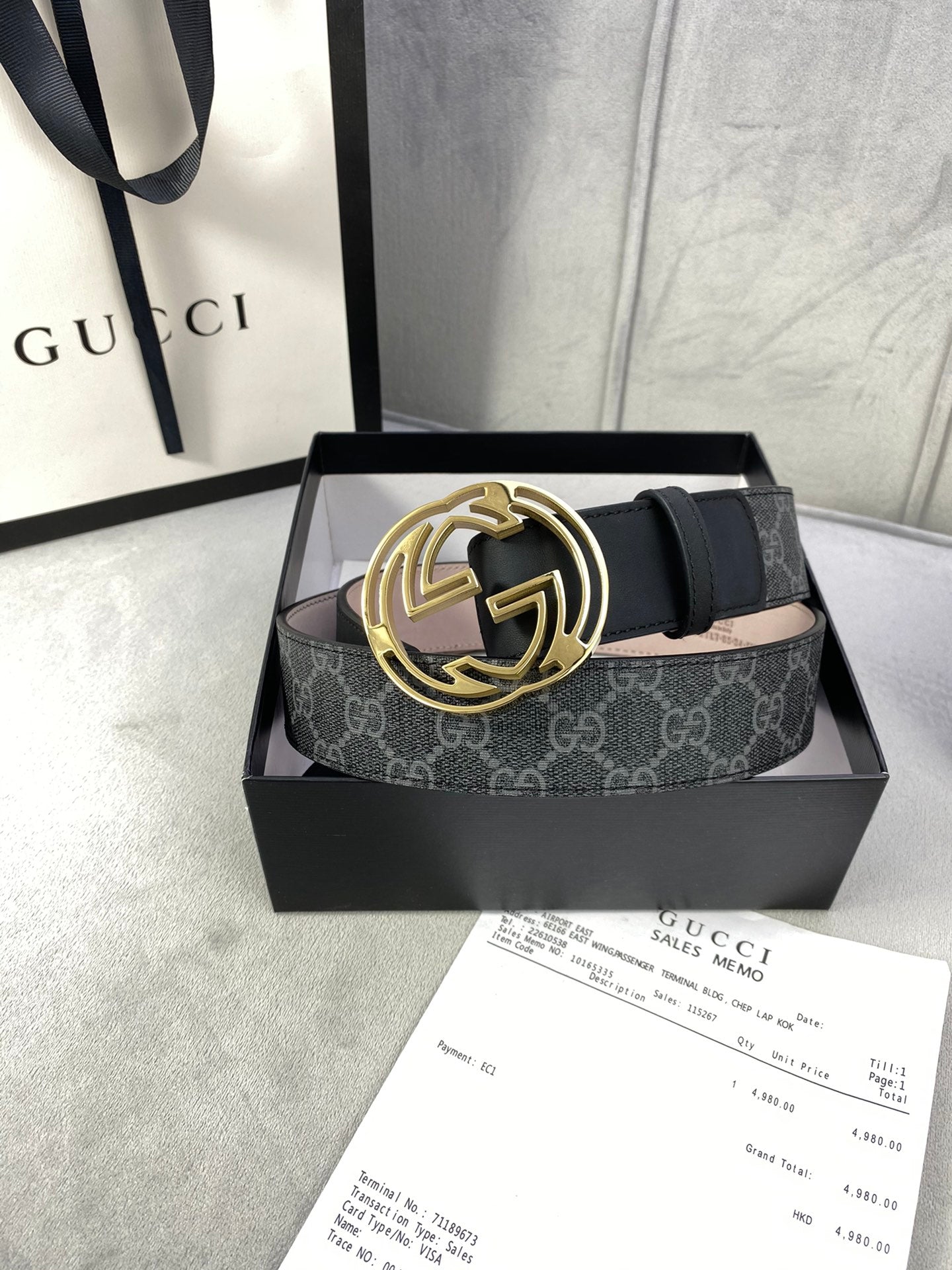 Black GG monogram belt with gold-toned interlocking logo buckle, laid across a box.