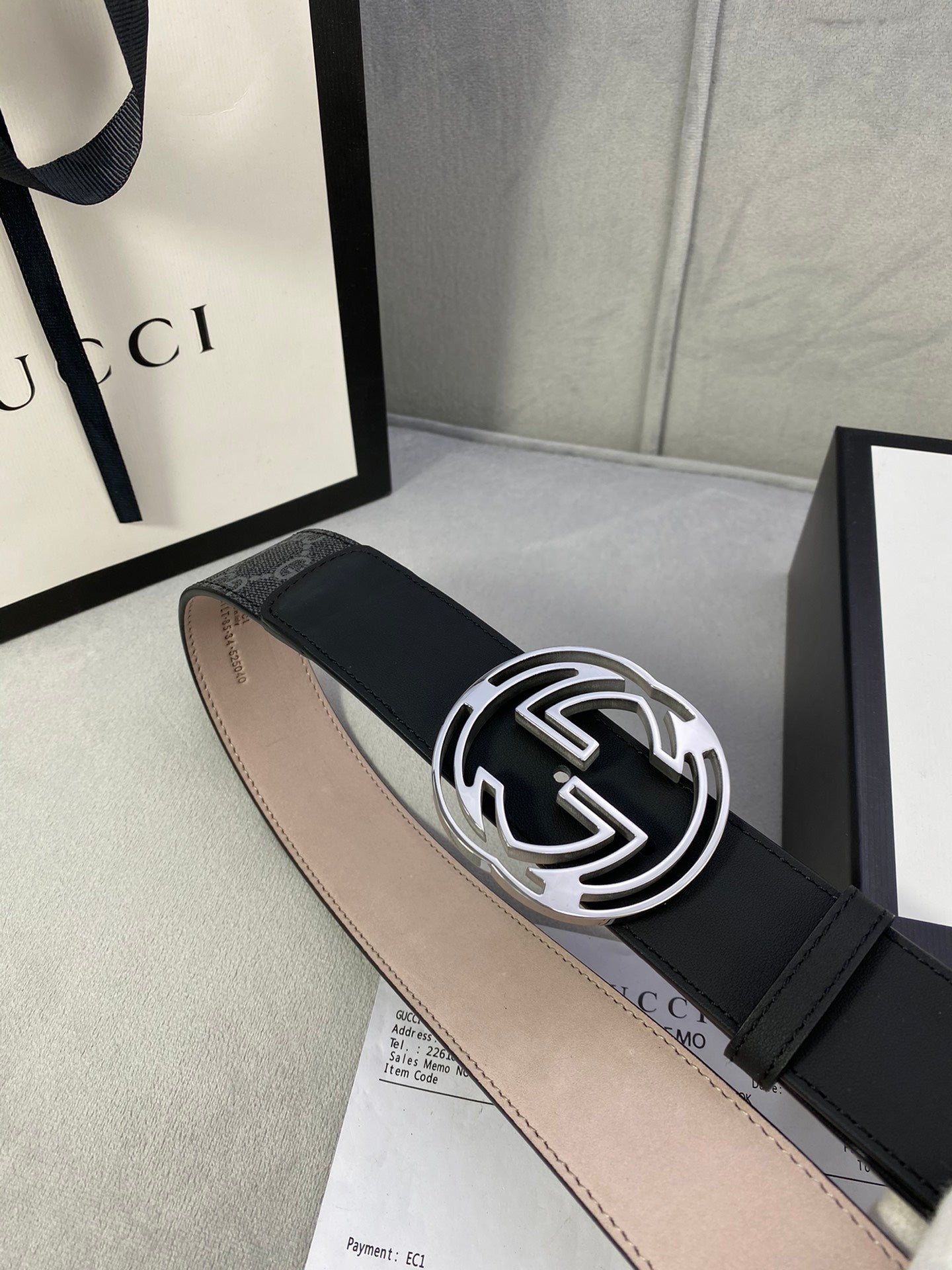Black GG monogram belt with silver interlocking buckle and stitched leather edge.