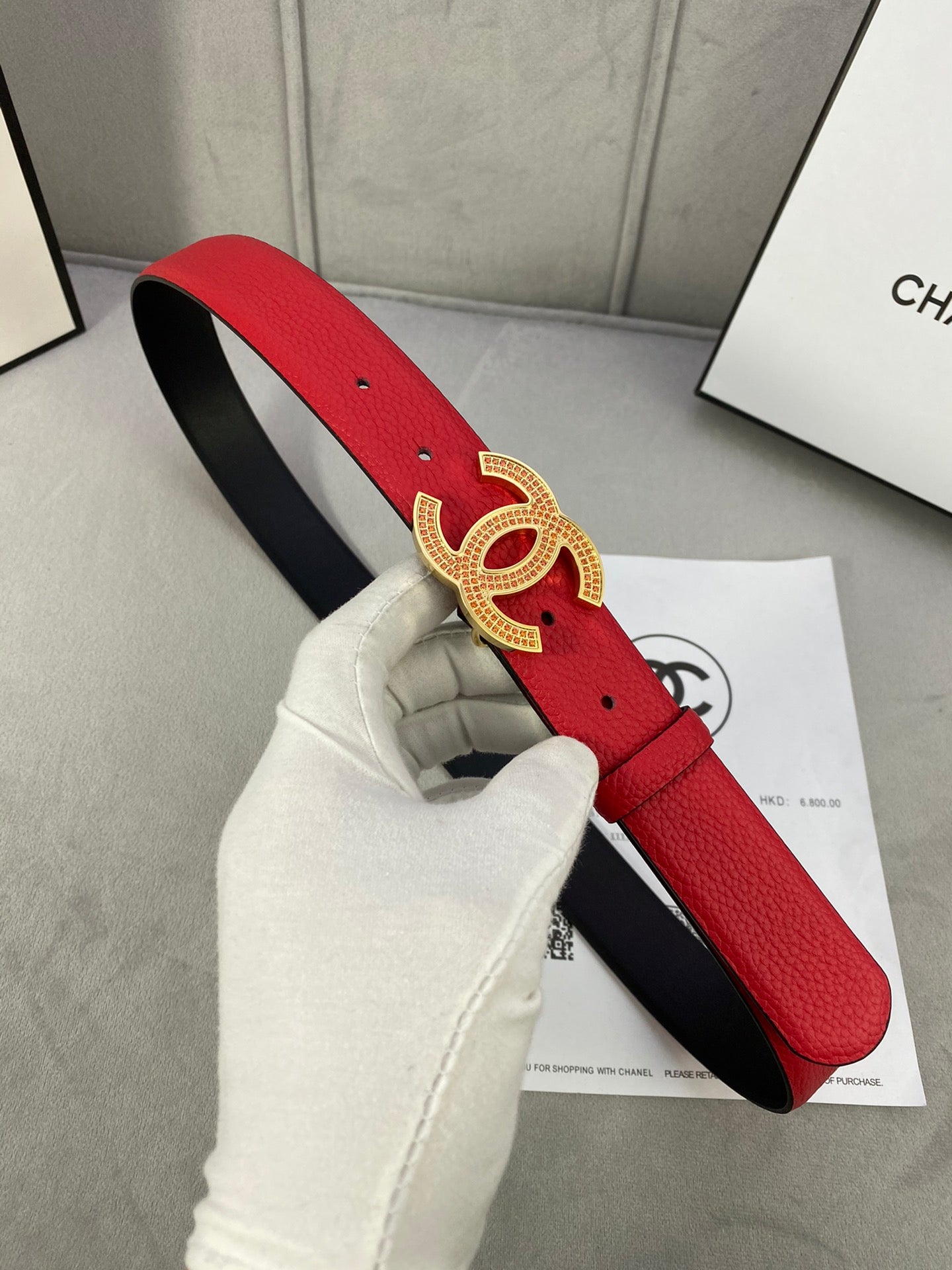 Red leather belt with gold CC-style buckle and black inner strap lining