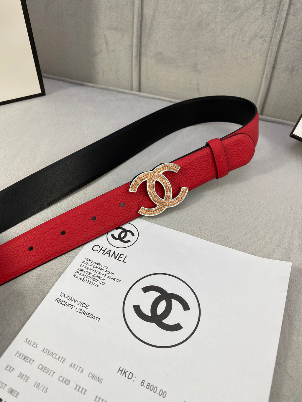 Red leather belt with gold CC-style buckle on black-lined underside