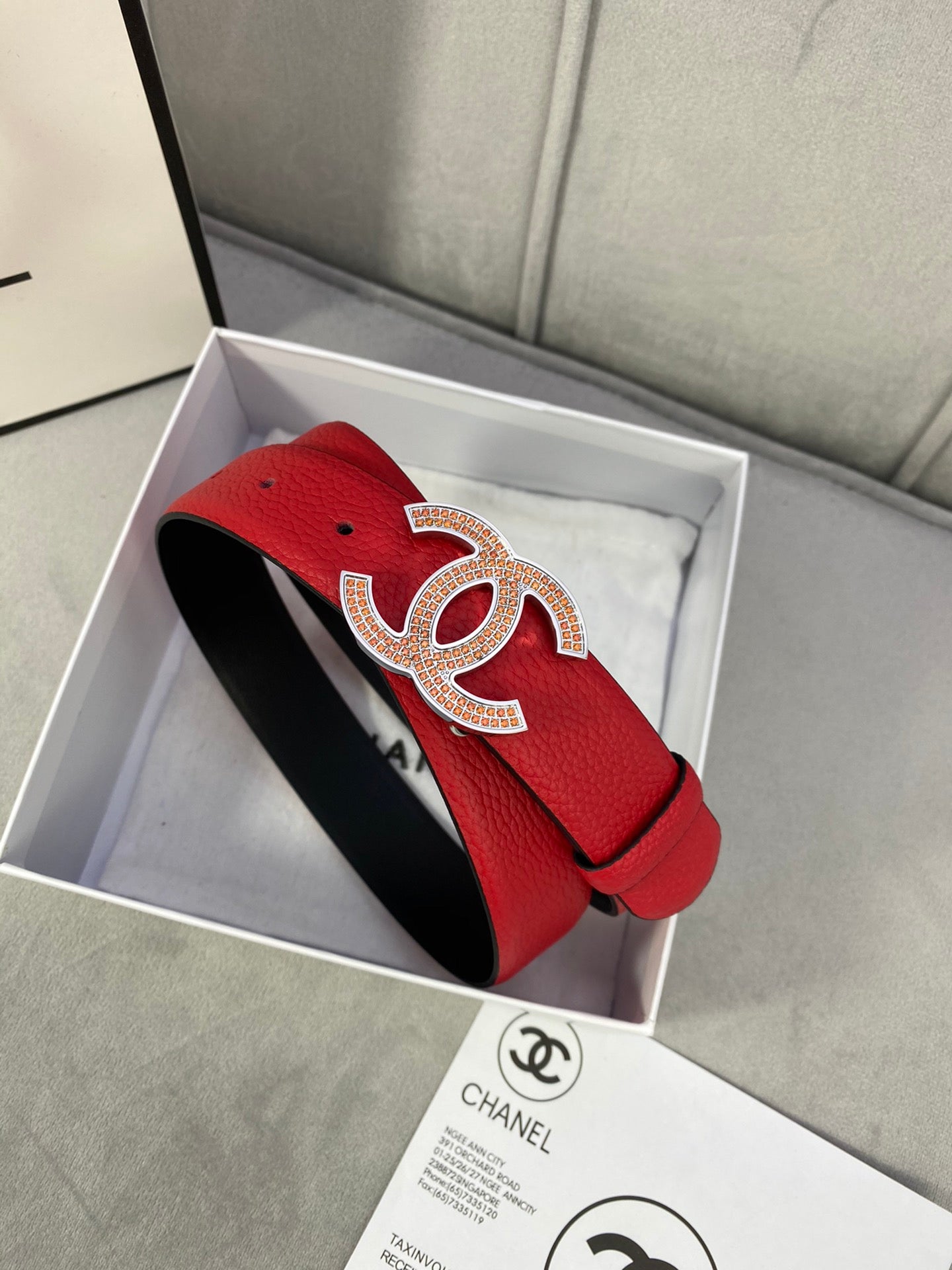 Red leather belt with gold CC-style buckle on a curved strap with holes