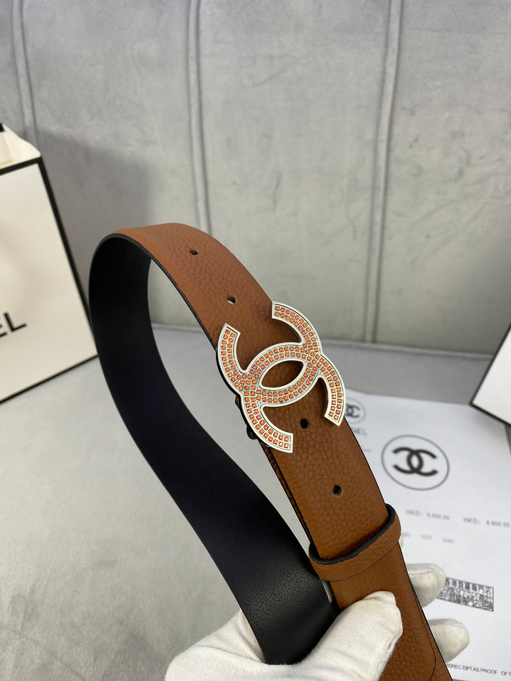 Brown leather belt with gold-toned CC buckle, dark strap underside showing