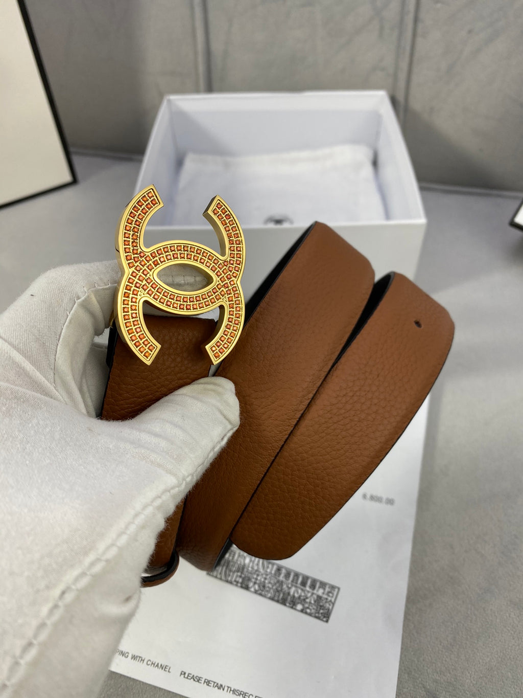 Brown leather belt with gold-toned CC buckle, leather texture visible