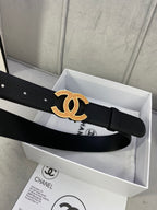 Black leather belt with gold CC logo buckle, strap end centered on a box insert.