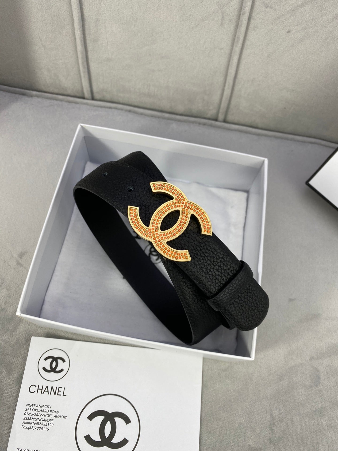 Black leather belt with gold CC logo buckle, packaged in a gift box with strap end.