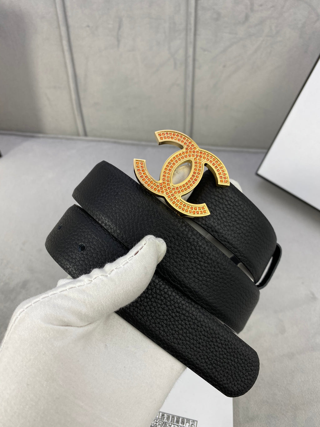 Black leather belt with gold CC logo buckle, adjustable strap with punched holes.
