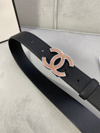 Black leather belt with orange-gold rhinestone CC buckle, strap stretched flat.