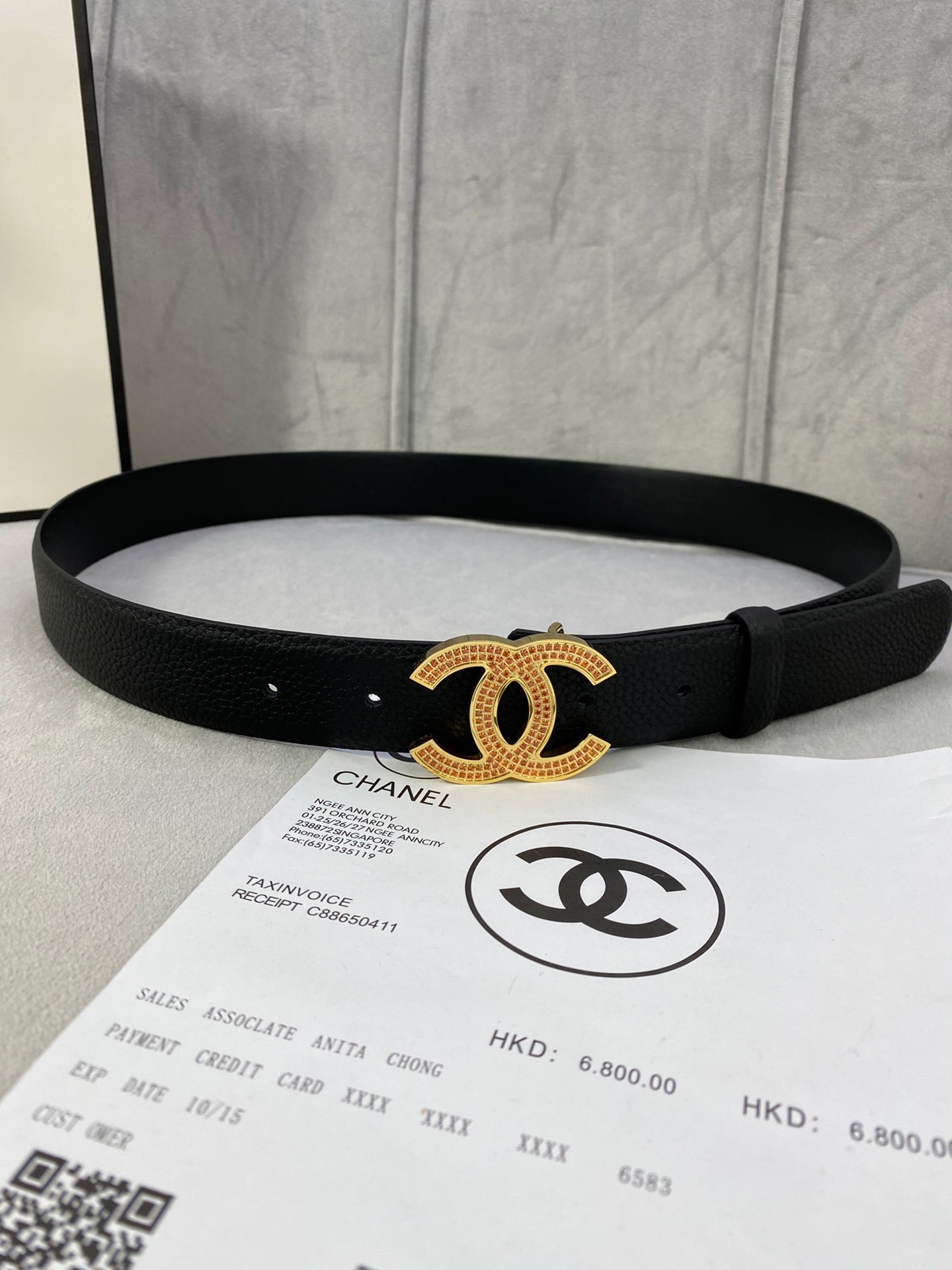Black leather belt with gold CC logo buckle, straight edge and punched adjustment holes.