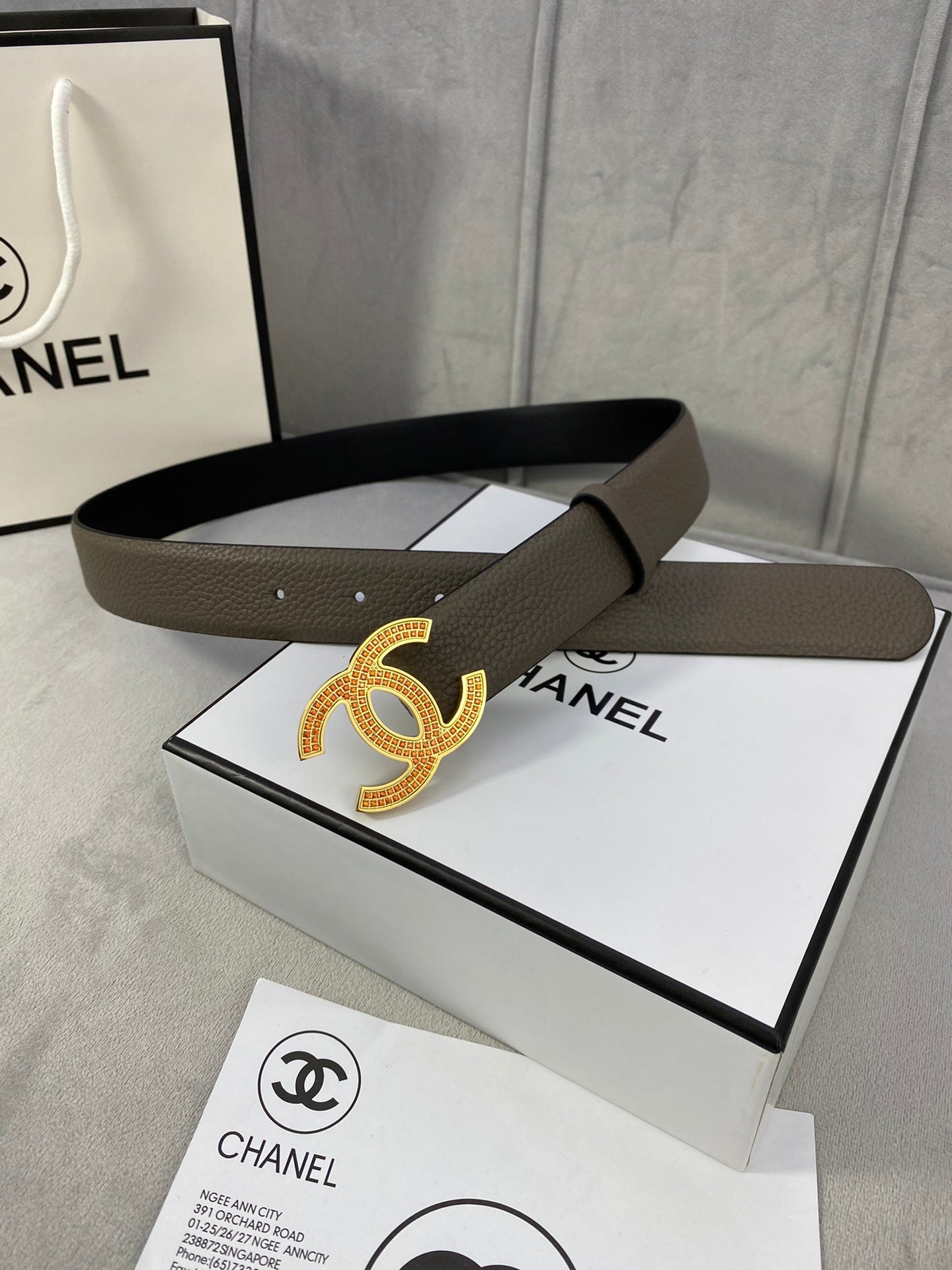 Chanel belt laid flat: dark taupe leather strap with gold CC logo buckle