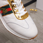 Close-up of white sneaker front: gold lace trim and multicolor logo panel