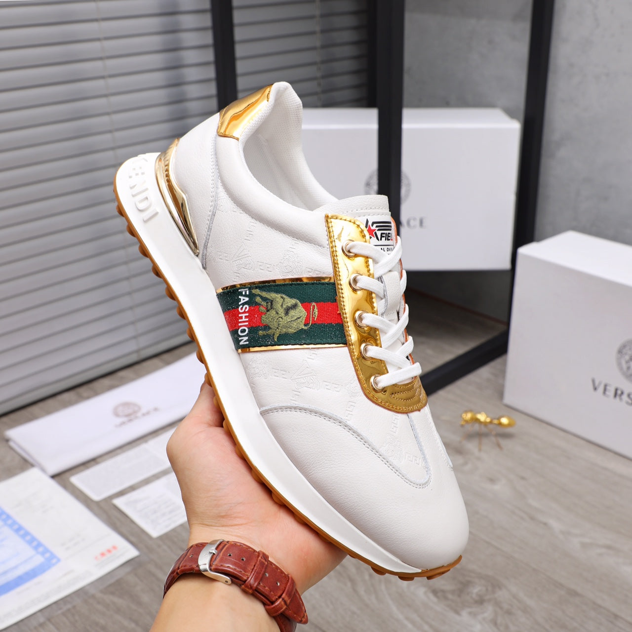 White lace-up sneakers with gold trim and multicolor logo panel on side