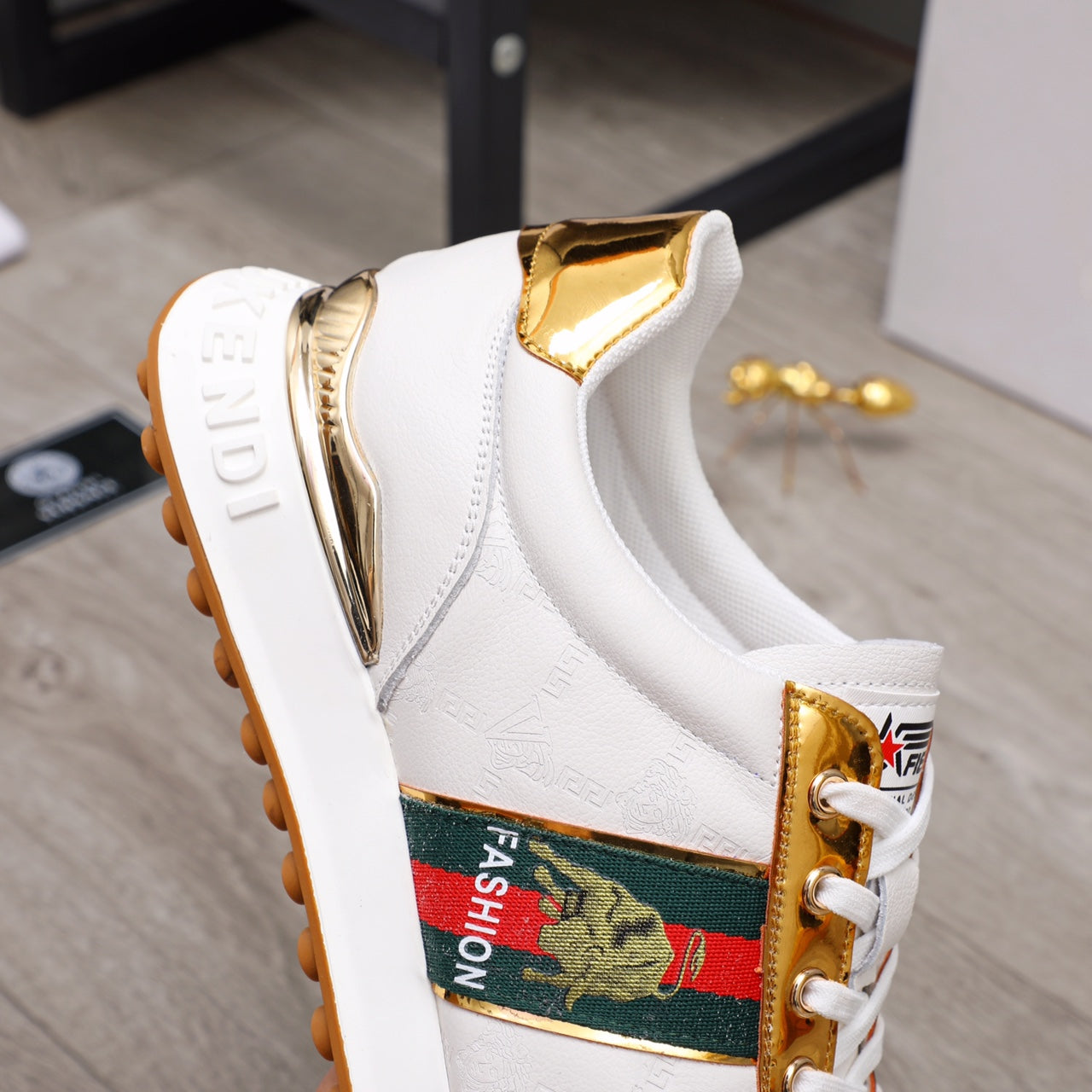 White sneaker side with gold heel detail, multicolor logo patch, lace-up